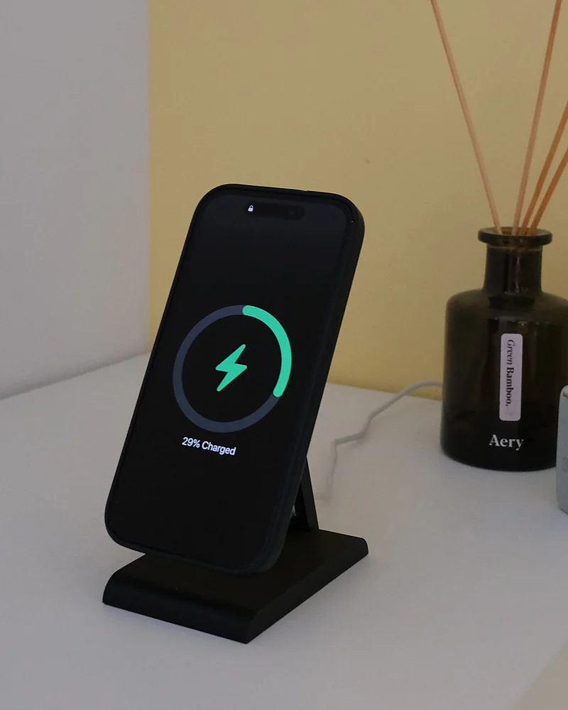 iPhone in carica sull'HPER, su un mobile bianco accanto a un diffusore