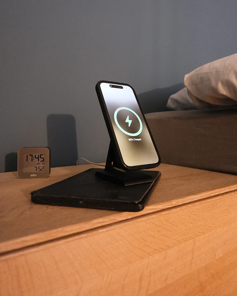 iPhone in carica sull'HPER, su un comodino accanto a una sveglia